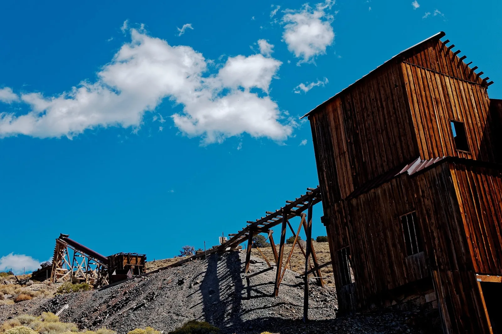 Sweeping high desert mining district in Nevada at golden hour, with open pit terraces visible on a distant mountainside