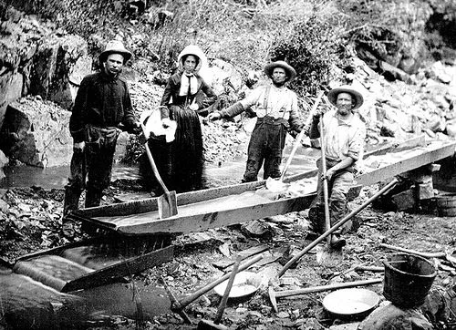 Three men and one woman panning for gold during the California Gold Rush, circa 1850